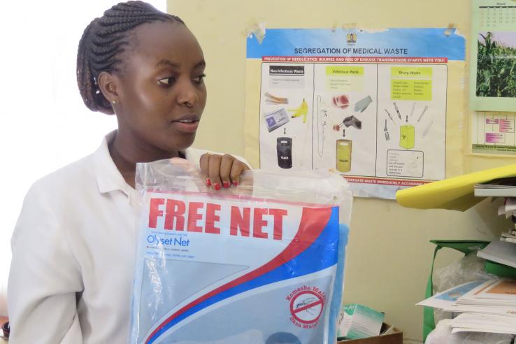 Woman in lab coat holds package reading "free bednet"