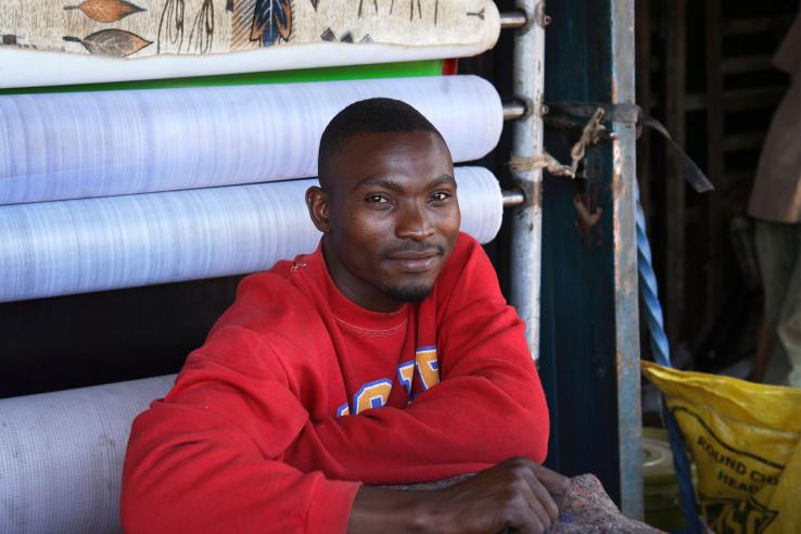 Man sits in front of rolls of cloth