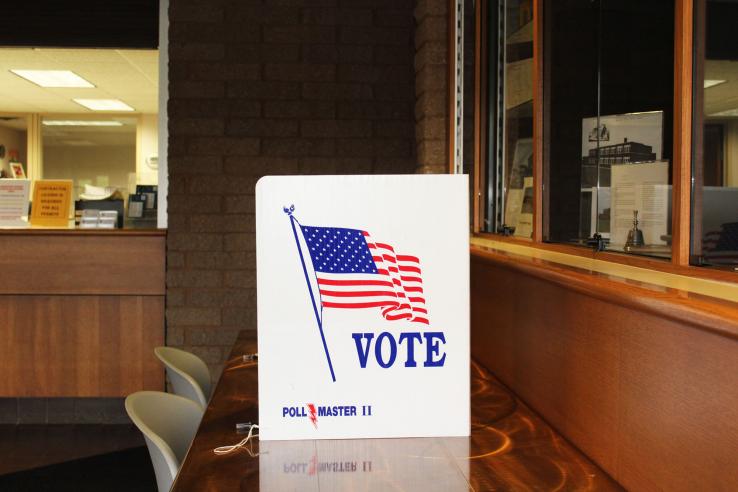 Empty polling place with privacy screen emblazoned with American flag and the word "vote"