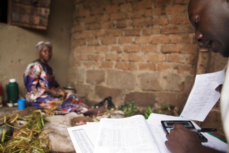 Man with calculator and paperwork in foreground with woman in background