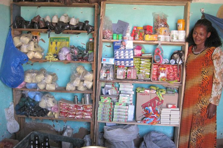 Woman in long dress next to two shelving units stacked with shoes and household wares