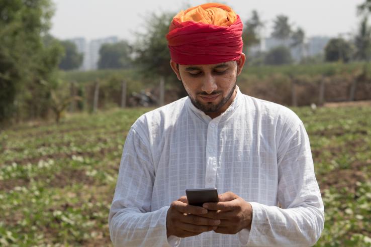 Farm worker text messaging on mobile phone in rural field