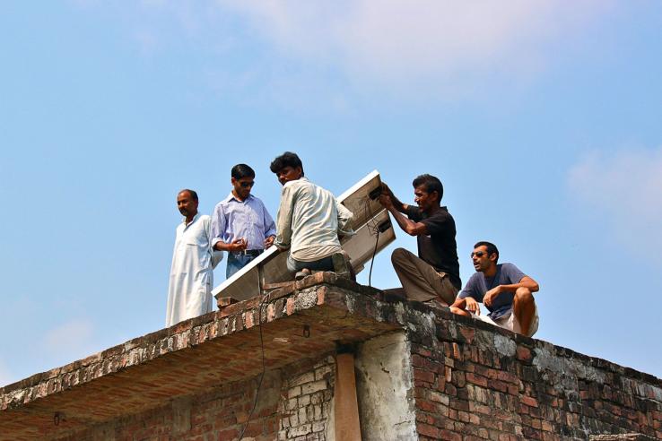 Group of men on the roof of a building installing solar panel