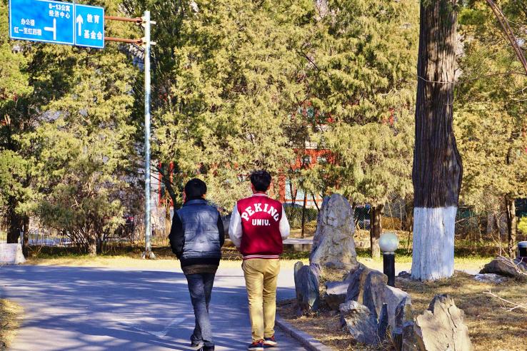 Two students walking: one's jacket reads 'Peking U"