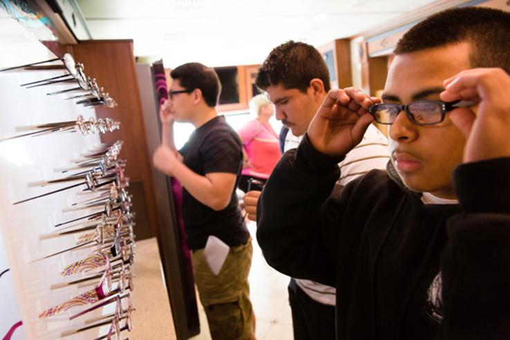 Three young men try on glasses