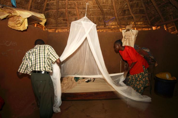 Man and woman assembling a bed net in rural Kenya.