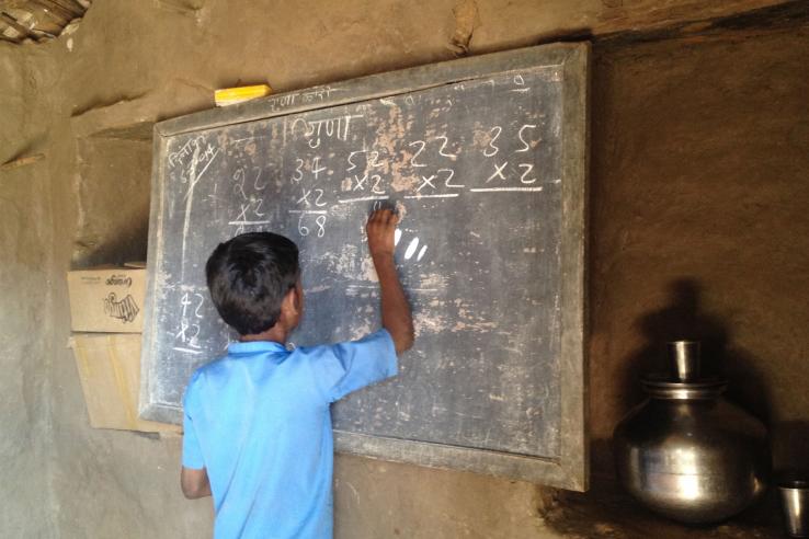 Boy writes sums on chalkboard