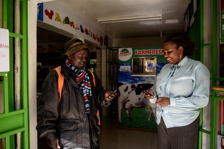 A man and women look at their mobile phones outside a shop in Kenya.
