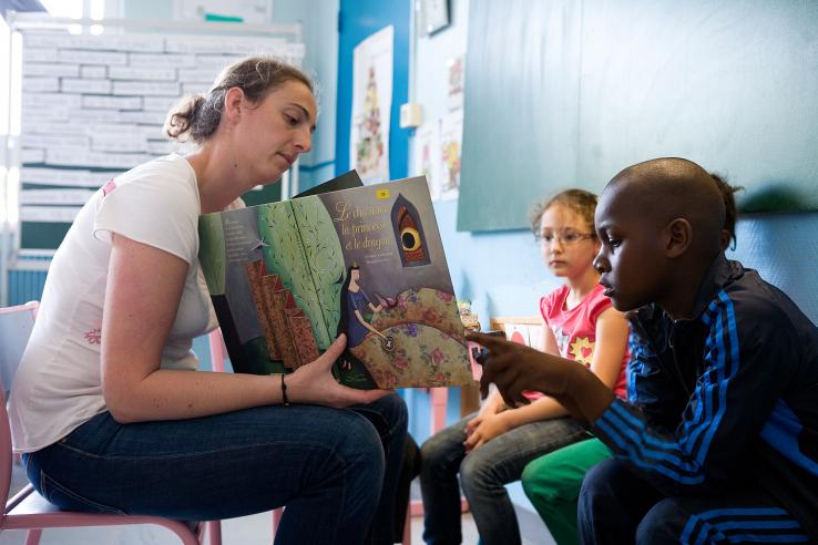 Tutor reads a book to children