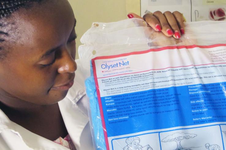 Woman receives a free insecticide-treated bednet at a health clinic in Kakagena County in Kenya