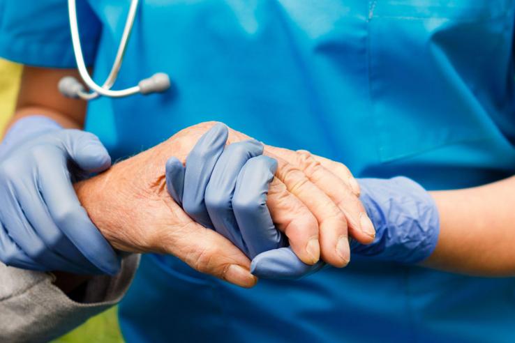 Doctor's gloved hands holding patient's hand