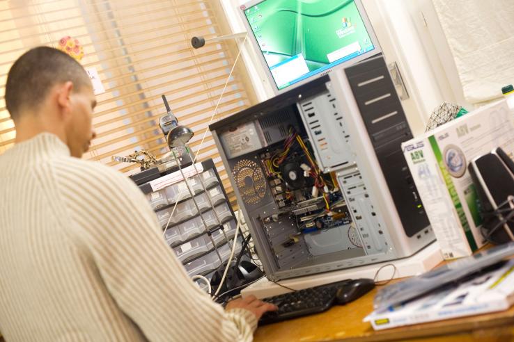 A young adult repairs a desktop computer.