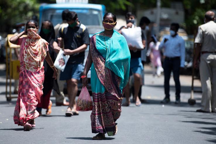 Women walk down a street wearing face masks