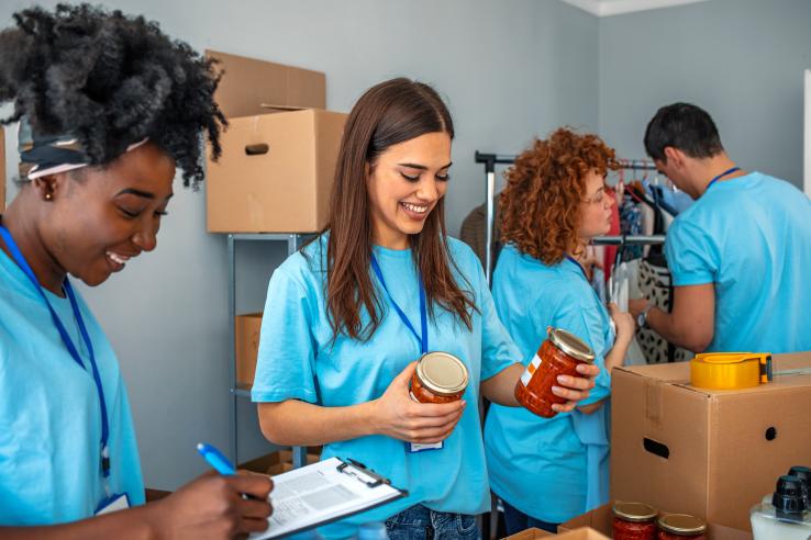 Young people in matching t-shirts sort cans.