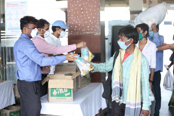 Aid workers in masks hand out kits to migrants in masks