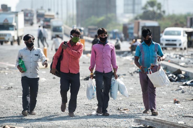 Four laborers wearing masks and walking in India during the lockdown