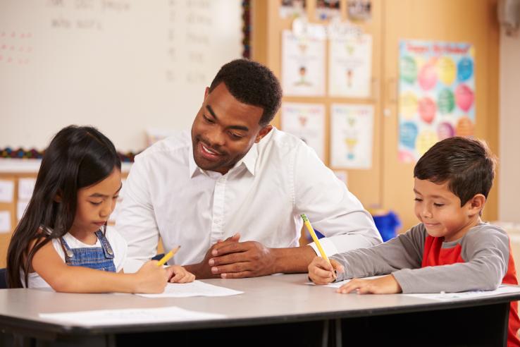 A man tutors two young students