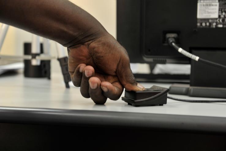 Hand providing thumbprint for biometric identification card
