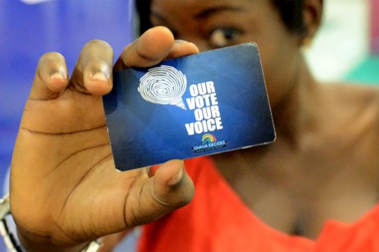 Woman holds a card that reads "our vote our choice" from Ghana Decides