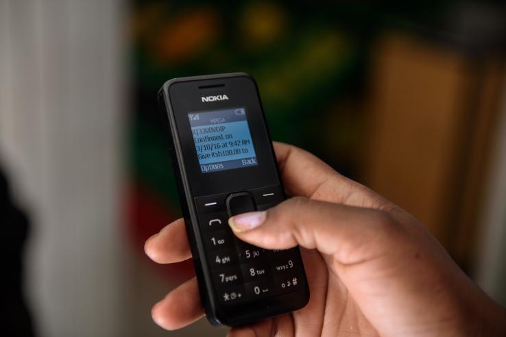 Hand holding mobile phone for digital cash transfer