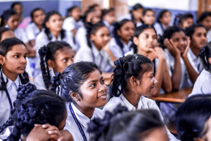 Girls in uniforms sit in a classroom in India