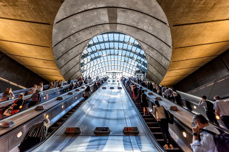 Commuters ride an escalator in London