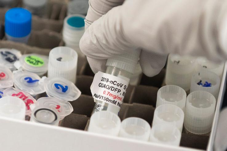 Scientist picks up test tube.