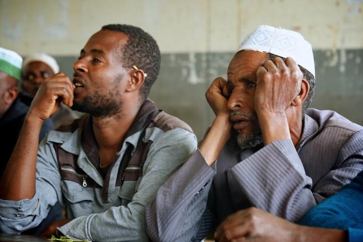 Two men sitting down listening to a facilitator of the UBL program