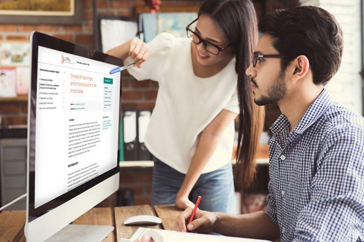 Women shows man new Evaluation Toolkit on computer.