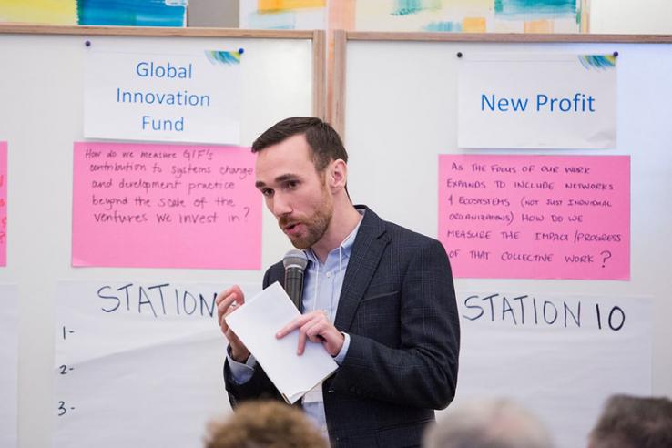 Michael Eddy speaks with a microphone in front of two whiteboards with notes on them