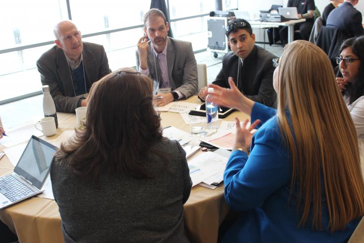 Conference attendees have a discussion around a table.