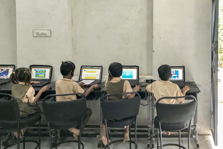 Four children in sit in the Mindspark lab in India, engaging with a learning program on their computers.