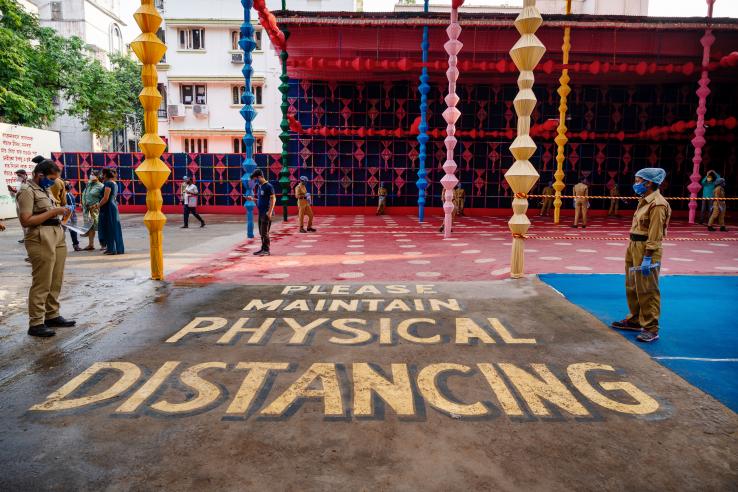 people gathered to celebrate a festival in Kolkata with a huge sign which says "please maintain physical distancing" painted on the ground