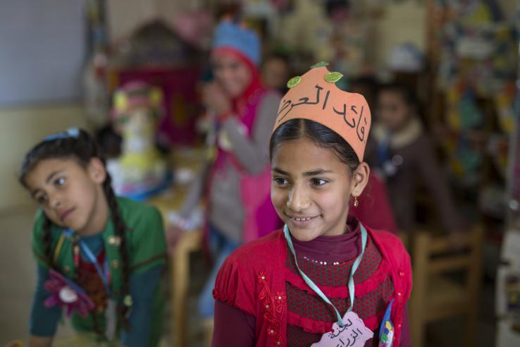 Young girl wearing a paper hat with other children