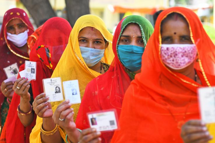 Women wait in line while holding up voter identification cards