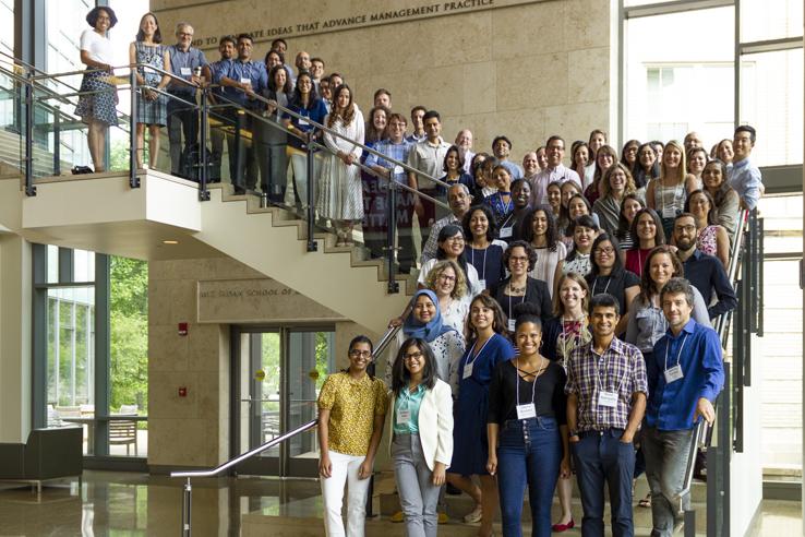 A group of J-PAL's worldwide staff pose on a stairwell on MIT's campus. 