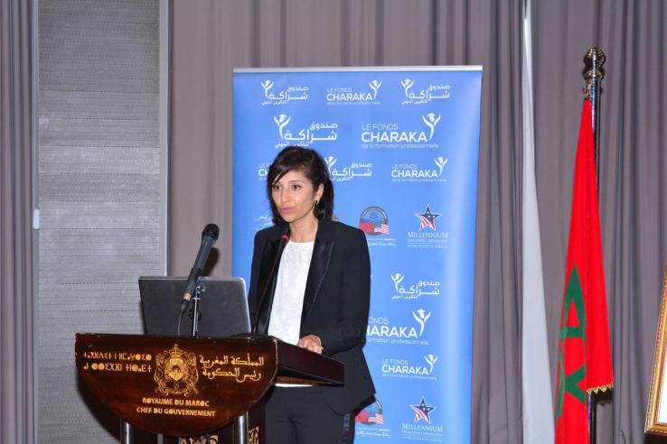 Hana speaks at a podium in front of a banner