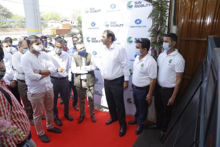 Jasmine Shah stands among a crowd of people looking at an electric vehicle battery swapping facility.