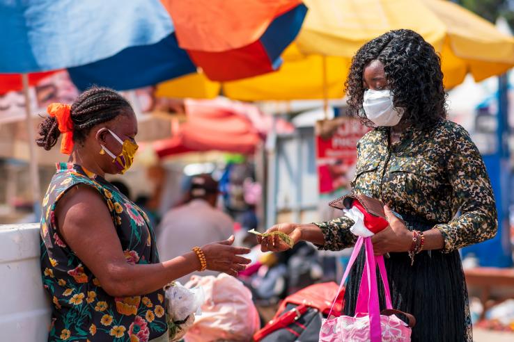 Masked women exchanging money at a market