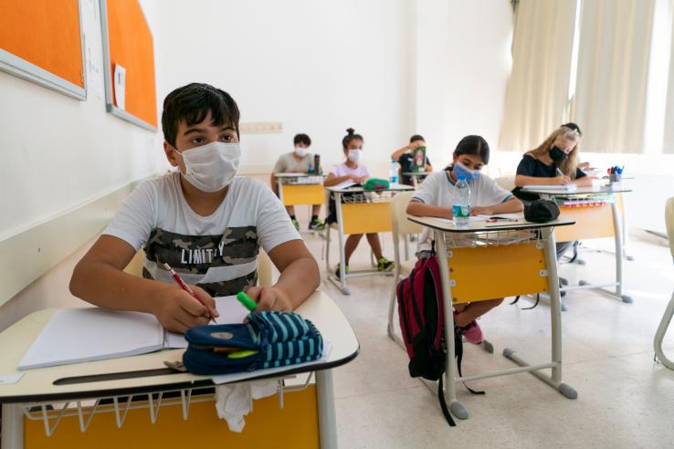 students wearing facemarks sitting at their desks in school