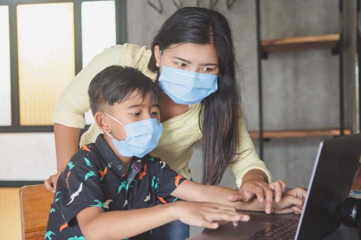 Mother helping child study online.