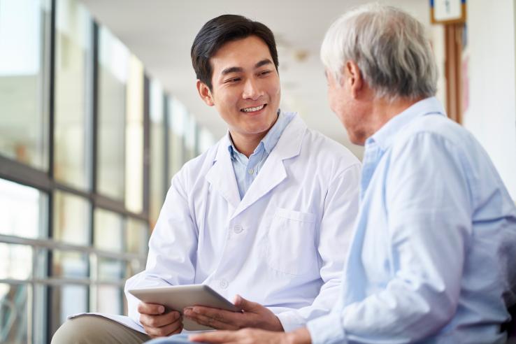 Two men, one wearing a lab coat, sit together and chat