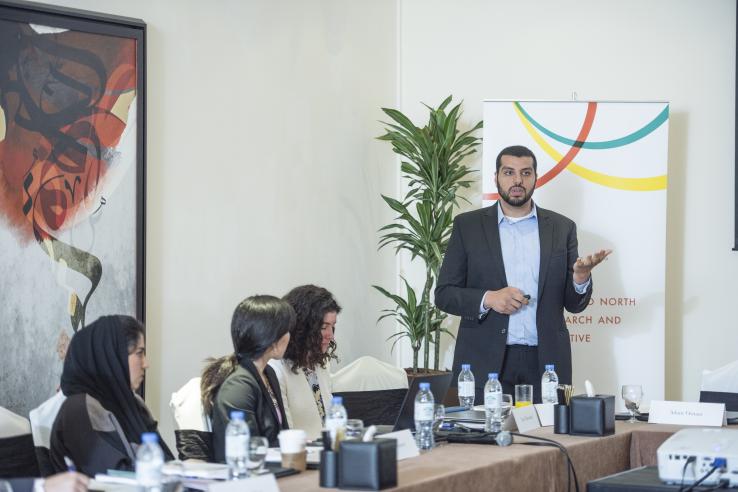 Adam Osman presents in front of a J-PAL MENA banner