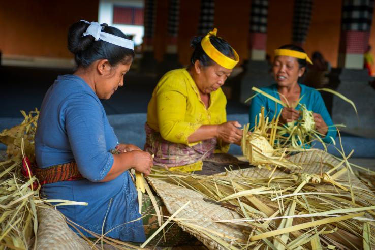 Three women make baskets for balinese traditional offerings to gods in temple Puru Tirtha Empul on Sep 21, 2012 in Tampak Siring, Bali, Indonesia
