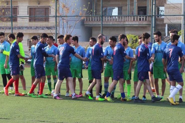 Mixed Christian and Muslim amateur soccer league groups greet each other before a game.