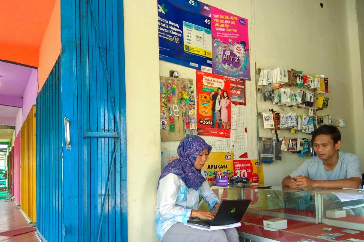 Researcher conducts a branchless banking evaluation spot check with an Indonesian shop owner.
