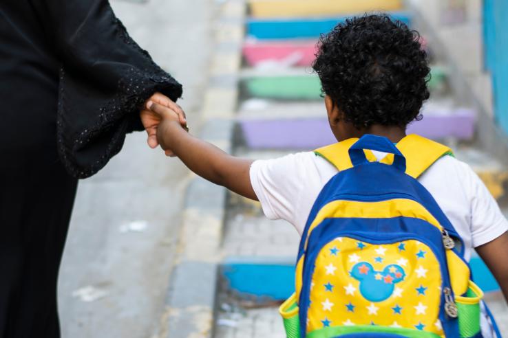 A young boy holding his mother hand carefully and peacefully while back from school in Alexandria, Egypt.