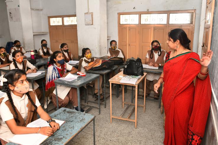 A female teacher leads a classroom lesson in India.