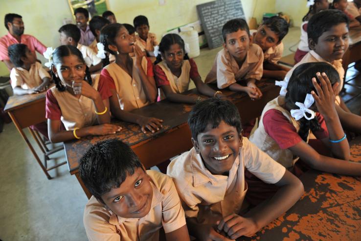 A group of children sitting inside a classroom in school 