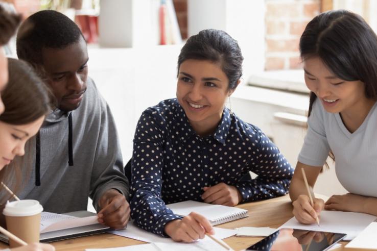 Five students with paper, pens, and iPads in conversation